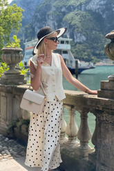 a lady in a white vest and a skirt with polka dots